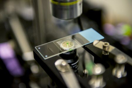 As they are cooled by the laser, the nanocrystals developed by the UW team emit a reddish-green “glow” that can be seen by the naked eye