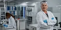Older woman with short hair in lab coat with arms crossed