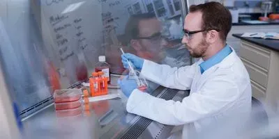 Scientist at a hood using cell culture media