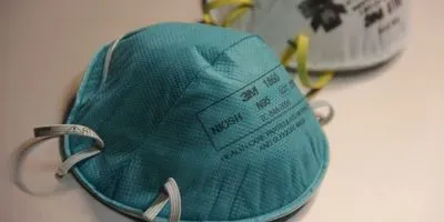 A green N95 respirator in the foreground, a gray one in the back