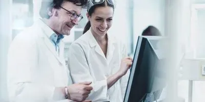 A male and female scientist working on a computer in the lab.