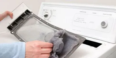 Person removing lint from dryer