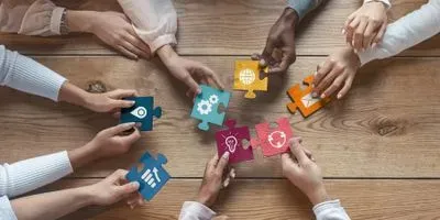 Image of a diverse team holding puzzle pieces 