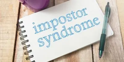 Note pad with the words imposter syndrome written on it