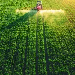 Tractor spraying a field of crops