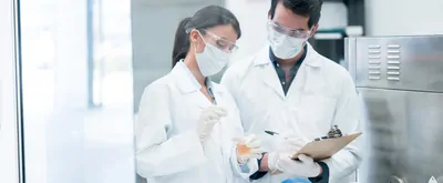 Couple of chemists working at the lab in a chemical plant and mixing products in test tubes