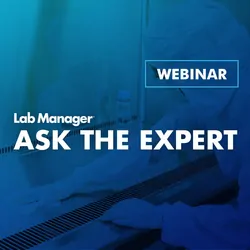 Lab worker, dresses in white PPE, sanitizing a biosafety enclosure
