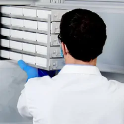 A scientist loading items into a cold storage freezer.
