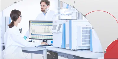 Two scientists in the lab talking over a computer.