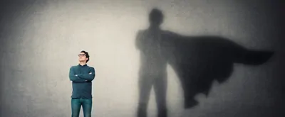 Person in superhero stance with shadow behind them in superhero cape