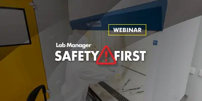 A scientist in sterile coverall gown pipetting medium or reagents for cell culture experiment in biological safety cabinet.