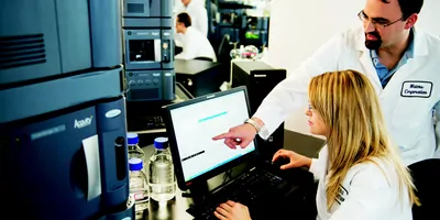 A bearded man and blonde woman look at a computer screen