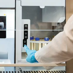 A scientist pressing a button on a lab instrument