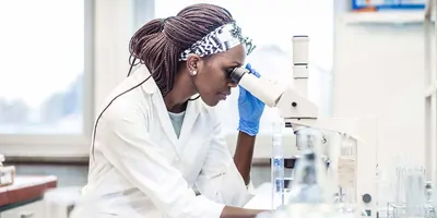 A scientist in the lab looking into a microscope.