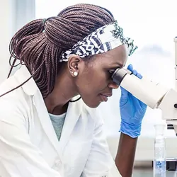 A scientist in the lab looking into a microscope.