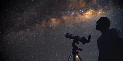 pserson using telescope to look at the stars at night