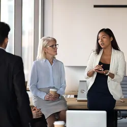 Women leading a meeting speaking with a bunch of adults in a circle