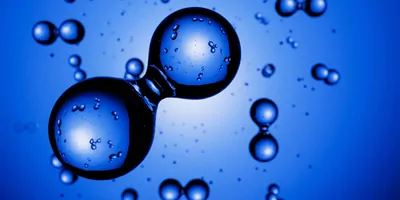 Glass beads reprsenting hydrogen atoms on a blue background