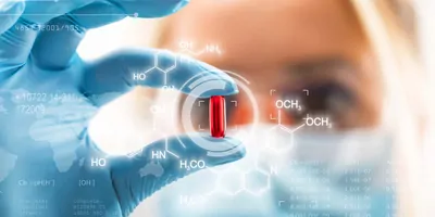 Women researcher, wearing gloves, holding a gel pill in her fingers up to her eye