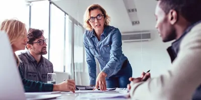 Young, happy woman presenting her idea to colleagues in a meeting.