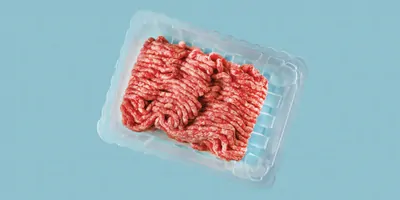 Ground beef or cultured artificial meat isolated on laboratory blue background. 