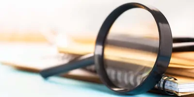 Magnifying glass leaning against a stack of journals