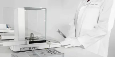 A photo of a scientist standing beside the Sartorius Cubis II lab balance