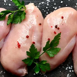 Raw chicken breast being seasoned