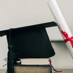 Graduation hat and scroll resting on books on a table