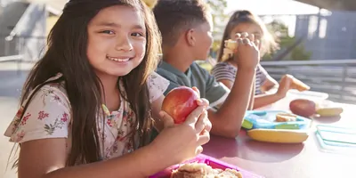 Children sharing a table and eating lunch outside