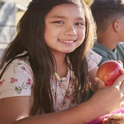 Children sharing a table and eating lunch outside