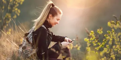 Women out doors, hiking, looking at her phone