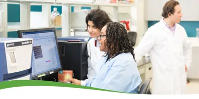 A photo of a group of scientist working with microplate technology in a lab