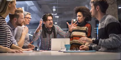 Man yelling at a mixed gender team of workers during a meeting