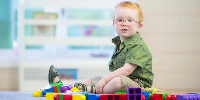 Toddler on carpet with toys illustrating teh importance of early autism detection in infant and toddlers