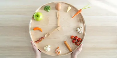 Clock made out of food, on a wooden table emphasizing that time of day eating is important for heart heath and diabtes management