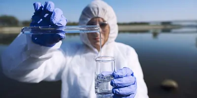 Close up view of ecologist sampling water from the river with test tube. Examining level of pollution. Conserve water and environment.