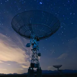 Satellite dish under the night sky pointed upwards