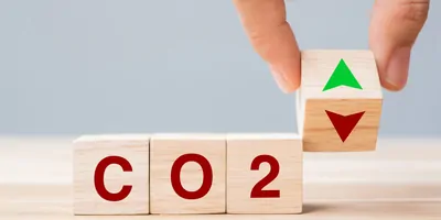 Hand flipping wooden cube blocks to UP and Down arrow symbol with CO2 (Carbon dioxide) text on table background