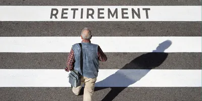 Older man crossing a crosswalk with the word "retirement" written on it