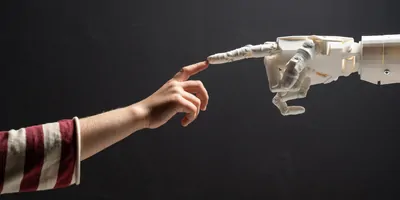 Human hand and robotic hand touching finger tips