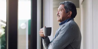 Shot of a senior man drinking coffee and looking thoughtfully out of a window