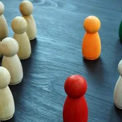 Wooden tokens that represent people lined up with white painted tokens on one side and multi-colored tokens on the other