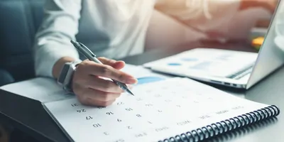 Person planning their monthly schedule on a calender