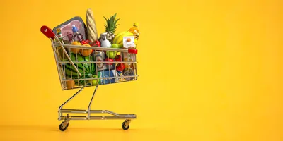 Grocery cart filled with food on a yellow background