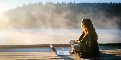 Women sitting on a dock during a foggy morning, looking out over a lake