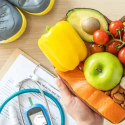 Heart shaped plate full of healthy food next to exercise shoes and a health chart