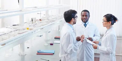 Three scientists talk in a lab