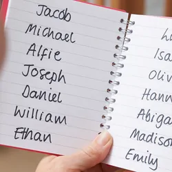 New parent holding notebook with a variety of possible child names in it 