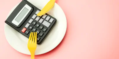 A calculator on a plate beside a knife and fork